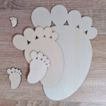 Various sizes of plywood baby footprint shapes arranged on a wooden surface