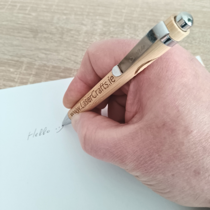 A person writing with a custom-engraved bamboo pen.