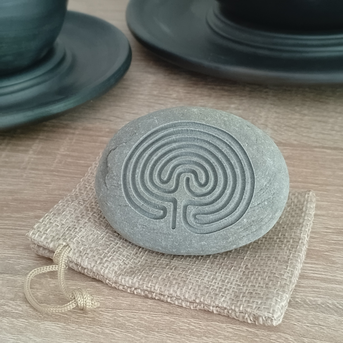 Engraved Cretan Labyrinth stone placed on a rustic burlap pouch, ideal for gifting.