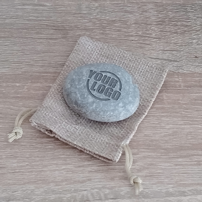 Custom engraved stone with company logo placed on a rustic gift pouch, ideal for corporate gifting and business branding.
