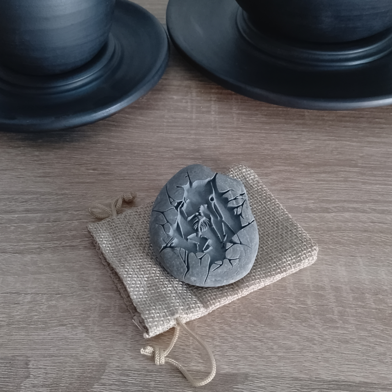 Engraved Pterodactylus fossil stone resting on a rustic burlap pouch, perfect for gifting.