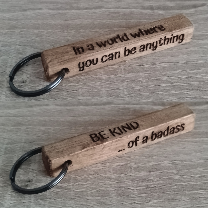 Wooden keychain showing all four engraved sides placed on a wooden surface