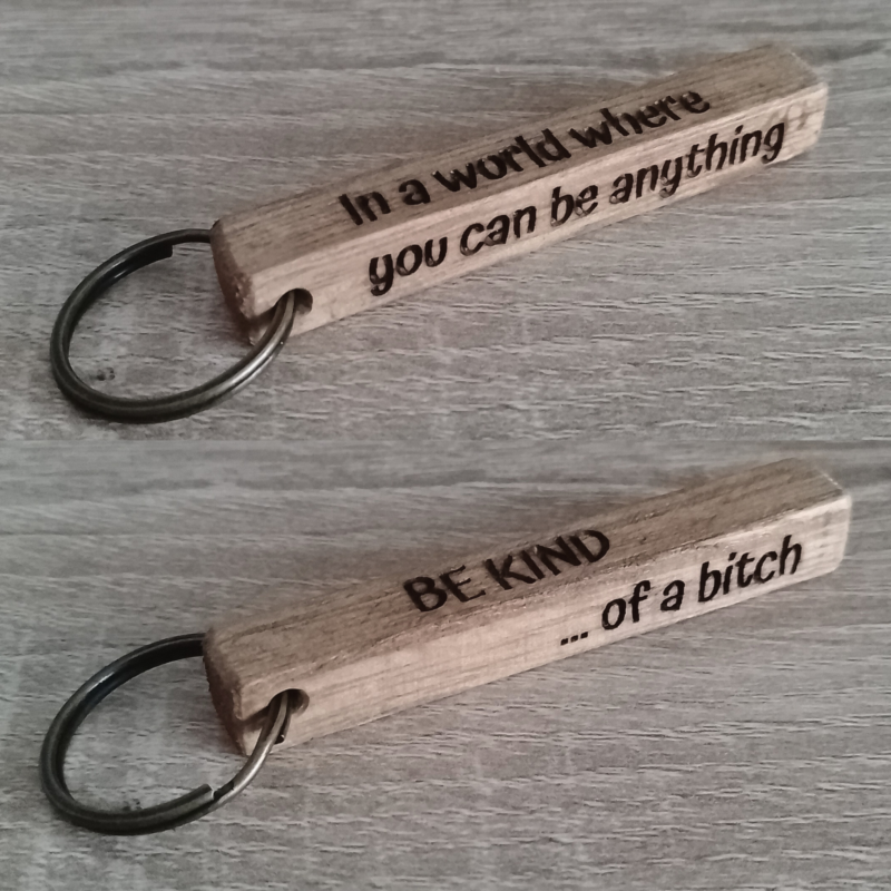 Wooden keychain showing all four engraved sides placed on a wooden surface