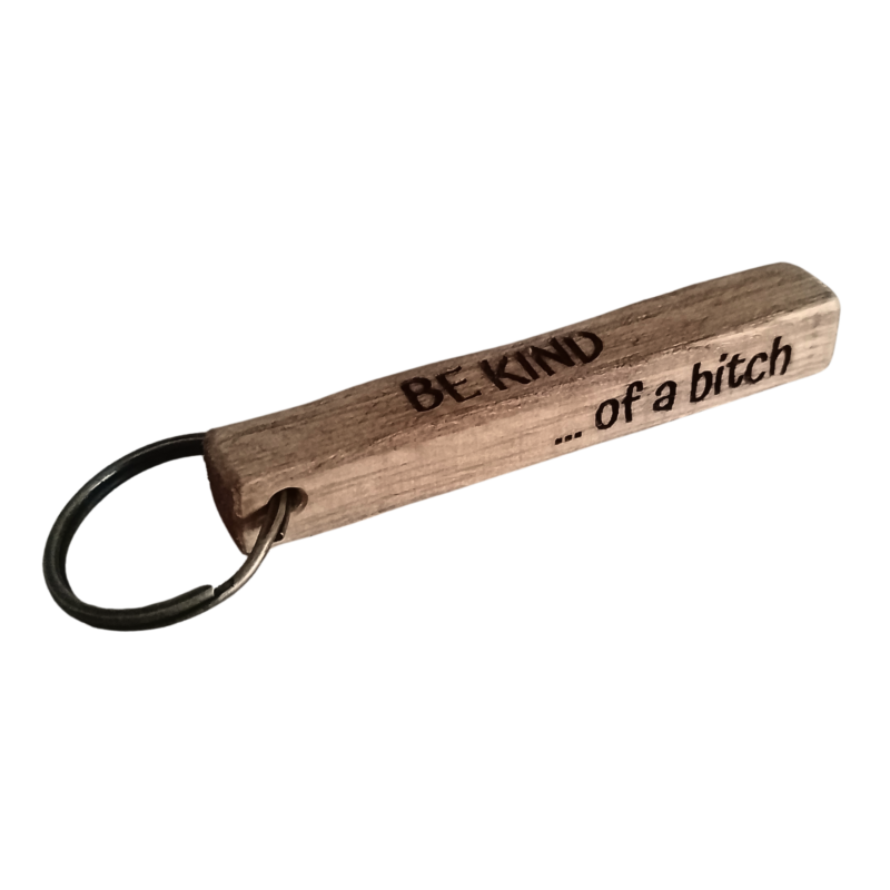 Close-up of wooden keychain with the engraving Be Kind... of a Bitch
