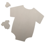 Close-up view of laser-cut plywood baby onesie shapes on a dark background