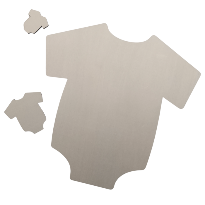 Close-up view of laser-cut plywood baby onesie shapes on a dark background
