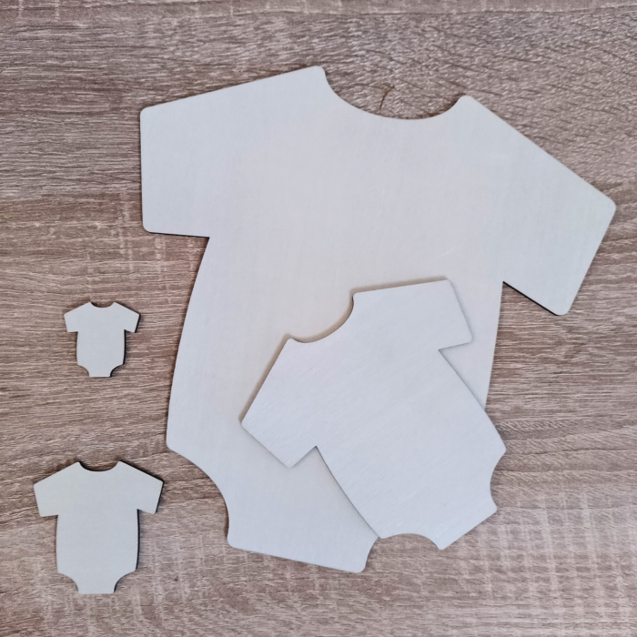 Various sizes of plywood baby onesie shapes placed on a wooden surface