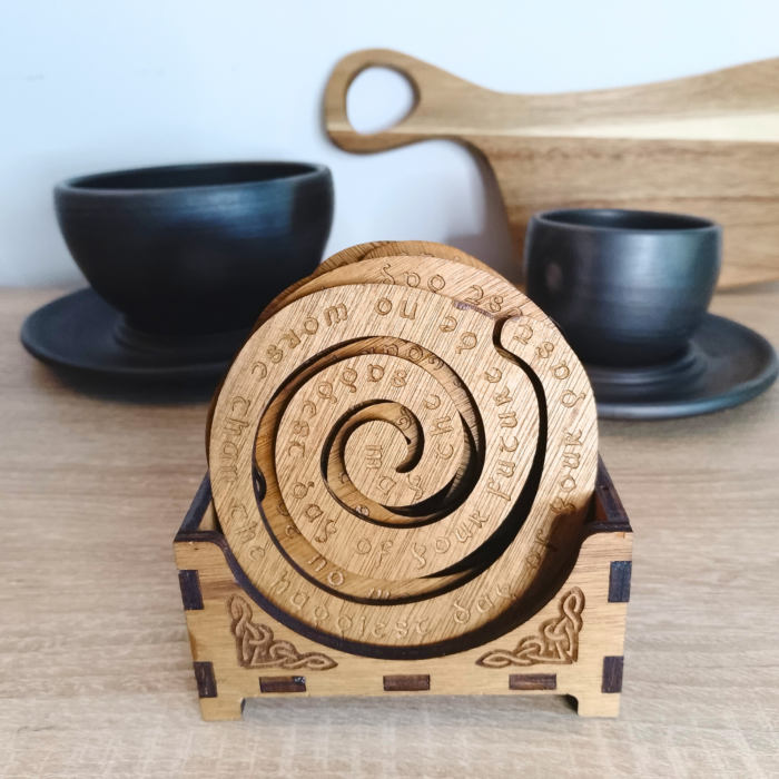Set of 6 spiral wooden coasters in a Celtic-inspired storage box, displayed with ceramic cups.
