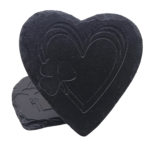 A heart-shaped slate coaster engraved with a heart and shamrock design, leaning against another coaster.