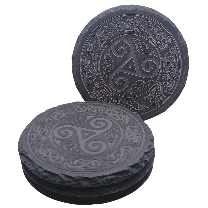 A round slate coaster with an engraved Triskelion design, displayed upright with other coasters stacked beneath.