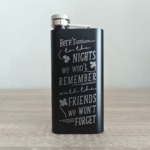 Black coated stainless steel custom flask with engraved funny Irish toast, front-facing on table.