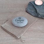 Personalised Pet Memorial Stone - Engraved pet memorial stone displayed on a table with a candle and fabric pouch.